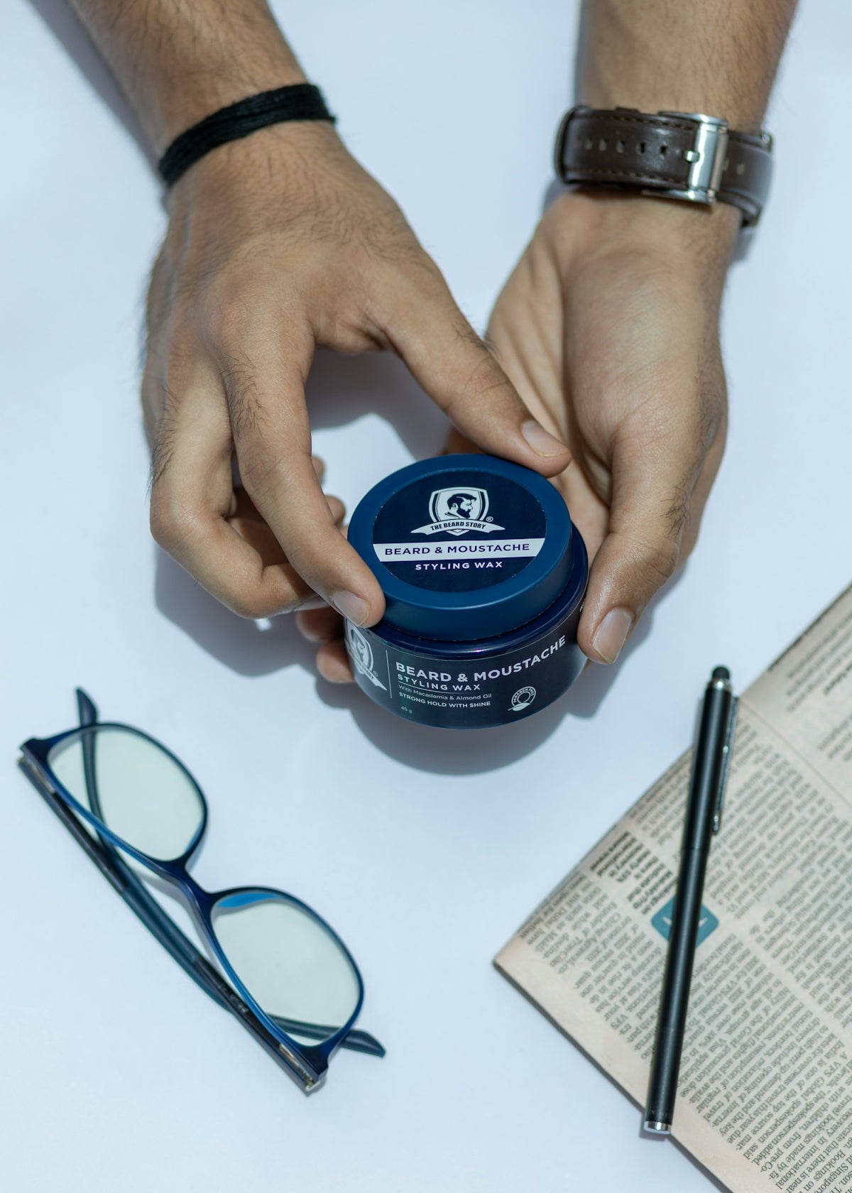 a person holding a jar of hair paste on top of a table